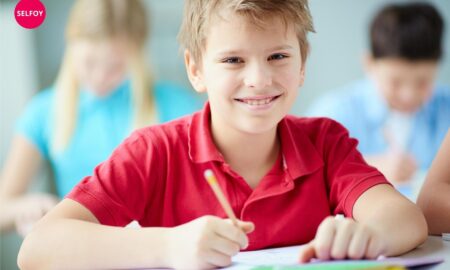 does autodidact work with self care? boy wearing red t shirt smiling having pen and notebook in his hand